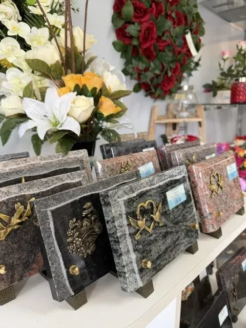 Plaques funéraires en granit exposées à côté d'un bouquet de fleurs.